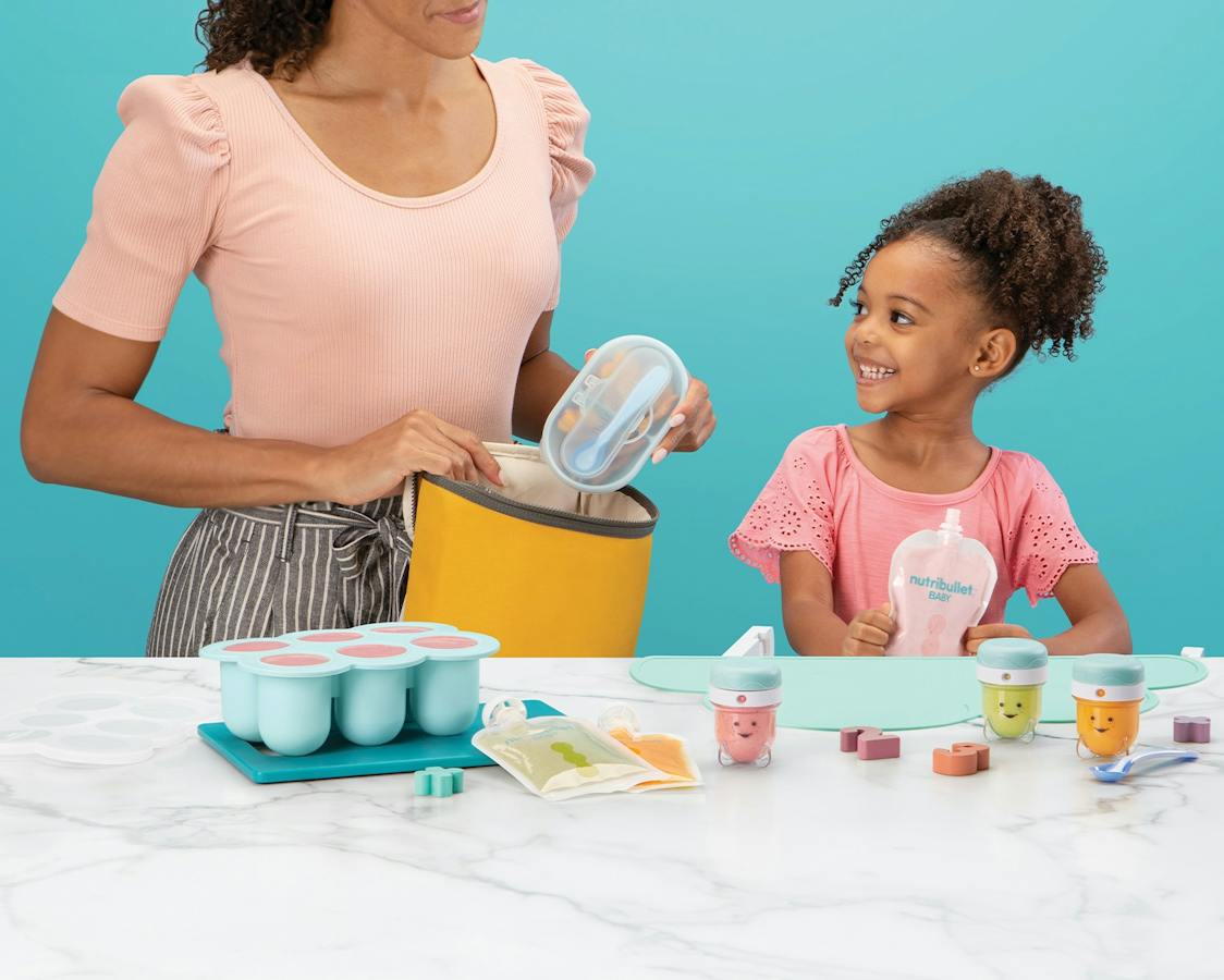 Woman with young girl with assorted nutribullet Baby products with a blue background.